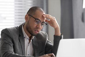 male professional looking wearily at laptop